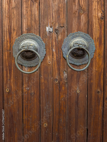 Ancient wooden door with ornate metal knockers, traditional architecture and history