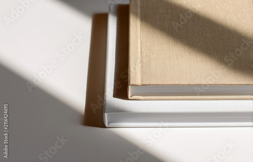 Close up of beige fabric cover photo book with visible weave texture and sharp page edges in soft sunlight. Ideal for photobook mockup, print product branding and professional portfolio display
