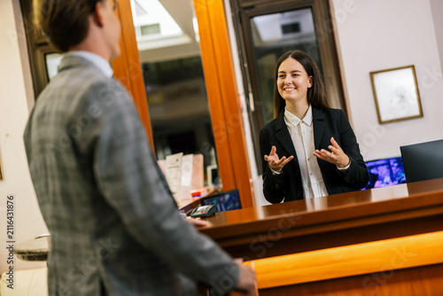 фотографія Receptionist assisting business guests at the front desk of a high-end hotel