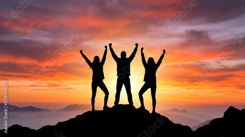 Group of Friends Raising Hands in Victory on Mountain Summit During Fiery Sunset