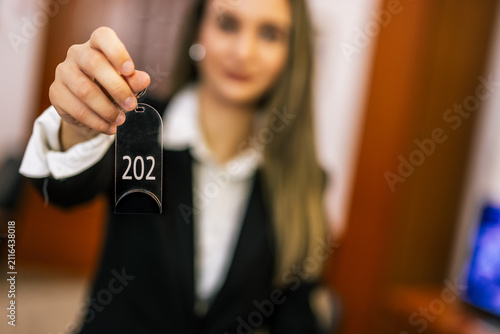 Close-up of hotel receptionist holding room key card toward the camera