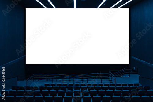Cinema hall interior view with rows of empty dark seats looking at large blank screen with transparent area for image replacement
