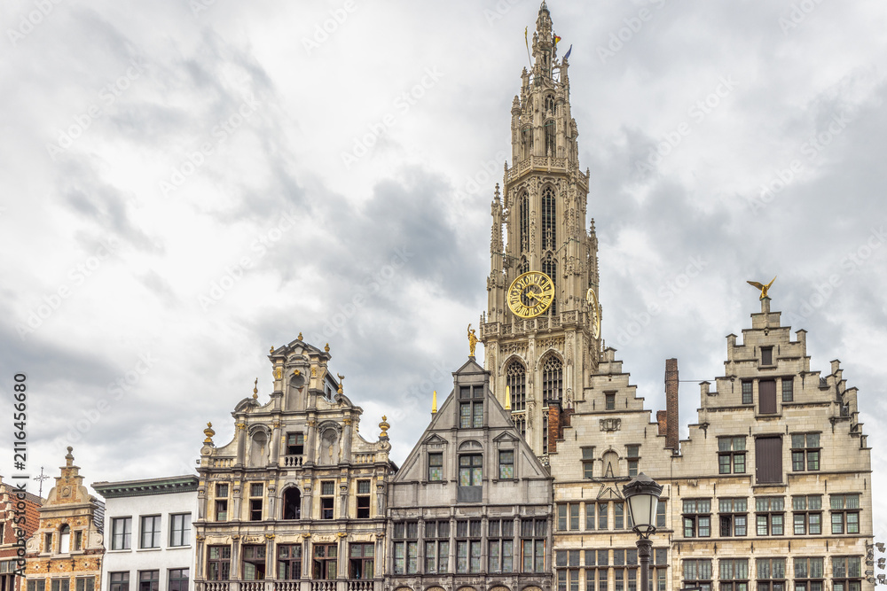 Obraz premium Antwerp town in Belgium, Europe. Dramatic View of Historic European Town Square with Grand Bell Tower and Ornate Gable Houses Under a Cloudy Sky