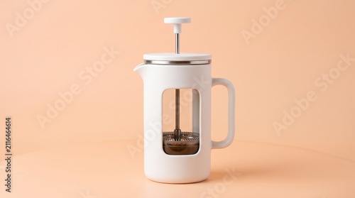 A modern white French press with a clear glass window standing on a warm peach background, ideal for stylish coffee brewing.