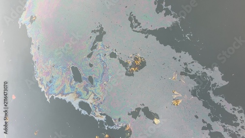 Iridescent oil slick polluting dark water surface
