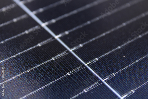 Macro modern solar panel surface featuring detailed photovoltaic cells, grid lines, and a textured finish with shallow depth of field