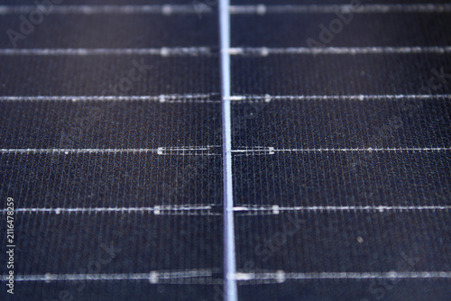 Close-up of a solar panel surface featuring textured dark blue cells and silver grid lines, showcasing renewable energy technology with selective focus.