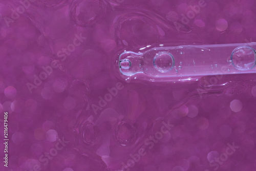 Принти на полотні Glass Pipette With Trapped Air Bubbles Suspended Over Pink Glitter Background Showing Liquid Texture, Reflective Highlights And Macro Detail In Closeup Cosmetic Concept Composition For Product