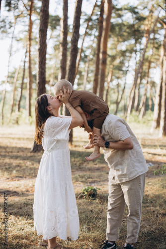 Young family enjoying summer outing in forest  mother kissing child on father s shoulders  happy moments