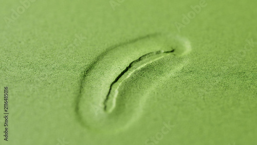 Single footprint indented in green sand surface with footprint indentation close-up depression landscape