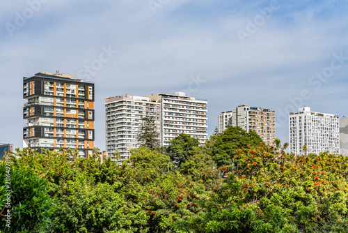 Modern residential high rise apartment buildings rising behind green park canopy in Lima, Peru
