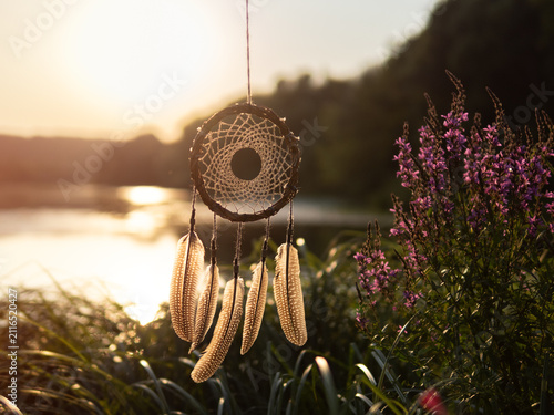dreamcatcher made of willow on the background of the river at sunset