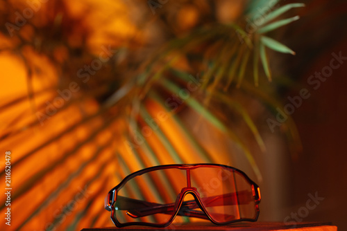 Sports photochromic glasses , sunset light and palm branches on the background