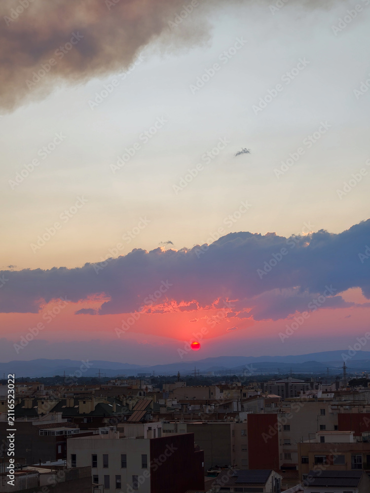 Obraz premium Red sun setting over almassora urban skyline