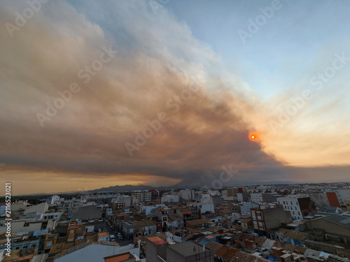 Wildfire smoke blanketing almassora city cityscape and red sun