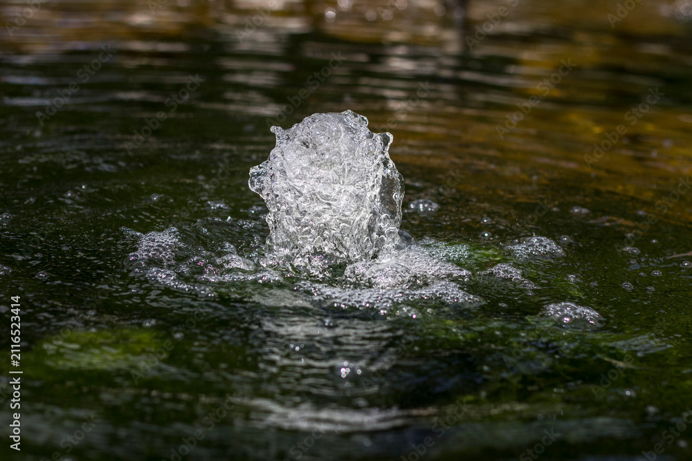 Fototapeta premium Water jetting upwards from a fountain capturing movement and bubbles on the surface