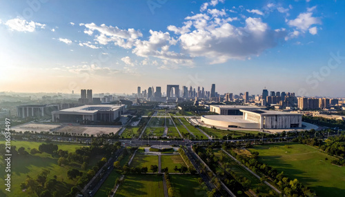Modern cityscape with prominent arch-shaped buildings under a wide blue sky dotted with clouds