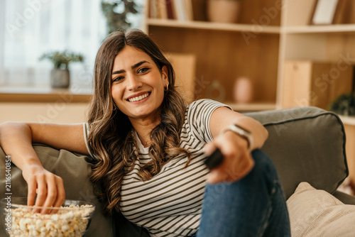 Cuadro en lienzo Woman smiling while relaxing on sofa watching tv