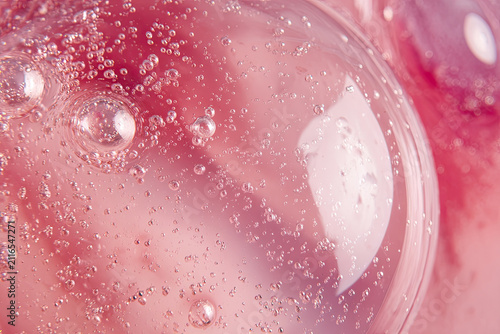 Beauty serum gel texture. Pink clear skincare cream with bubbles background. Transparent colored cosmetic product close up 