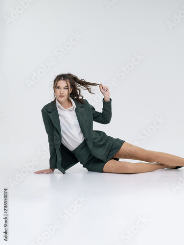 Canvas Print An elegant white woman in business suit talks on a red telephone while sitting on a chair against the backdrop of an isolated space