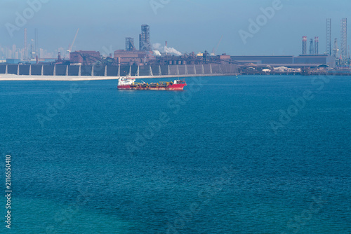 Bore drilling vessel in Bahrain port with industrial infrastructure, Persian Gulf