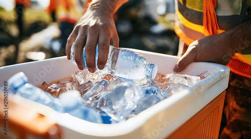 Worker opens cooler with ice and water bottles at construction site