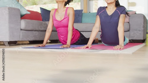 Mother and daughter pressing hands, lifting chest, deepening backbend on blue pink mats for fitness
