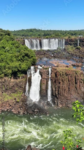Daytime landscape of the upper and lower Iguazu Falls on the border of Brazil and Argentina, with powerful white water cascading over basalt rock formations and surrounded by lush greenery