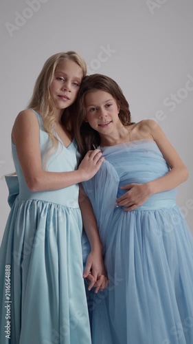Teenage children in elegant dresses are gently hugging. Concept of youthful friendship.