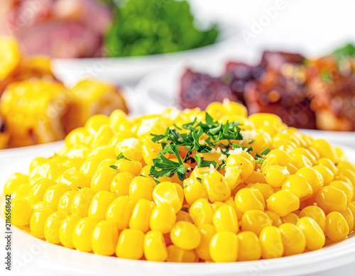 Side dish of yellow corn, blurred food in the backdrop. AI