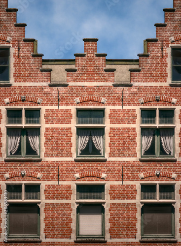 Perfectly symmetrical architectural composition showing the ornate brick facade, stepped gables, and classic multi-pane windows of an old European building.