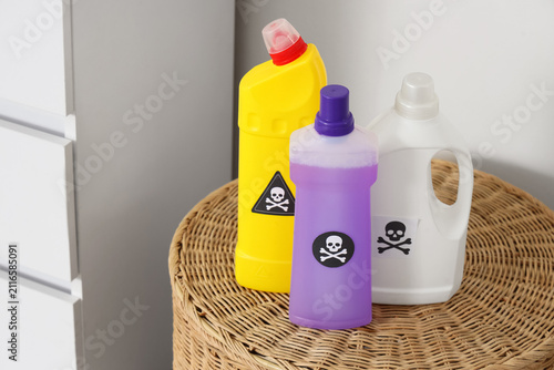 Household cleaning products with skull and crossbones warning labels on a woven wicker surface, chemical safety and danger