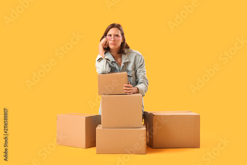 Konstfotografi Beautiful young sad woman with many parcels on yellow background
