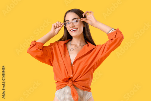 Pretty young woman with eyeglasses on yellow background