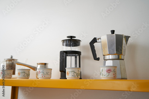 Italian moka pot and French press on modern kitchen shelf