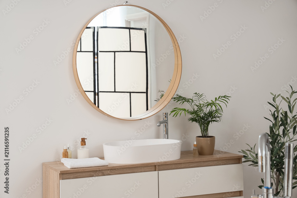 Obraz premium Sink with cosmetic products and palm on drawers in bathroom