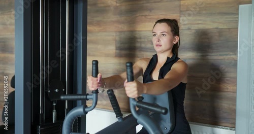 Fit young woman exercising on pec deck machine at the gym