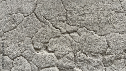 Obraz na płótnie Close‑up of cracked roughcast plaster wall with irregular stucco patches and visible fissures, creating an abstract textured background with weathered architectural character