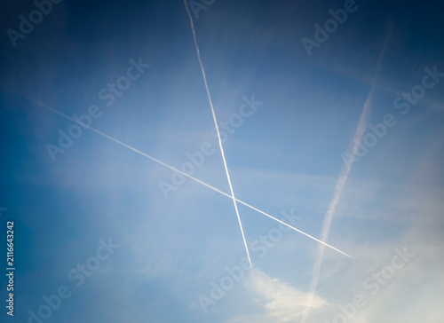 Cuadro en lienzo Airplane contrails crossing a clear blue sky, white vapor trails creating an abs