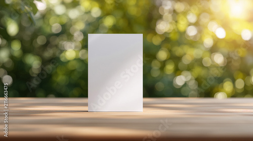Blank White Vertical Card Mockup on Wooden Table with Blurred Natural Green Forest Background and Sunlight