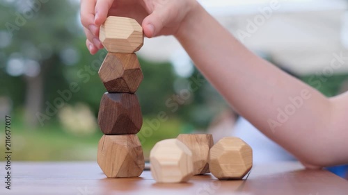 Man placing a wooden Tumi Ishi balancing block on a tower in a Japanese garden, close up