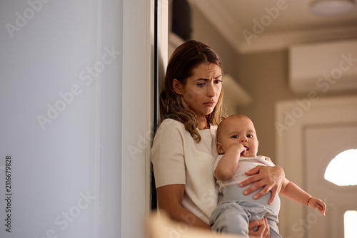 Young depressed mother with her baby boy at home.