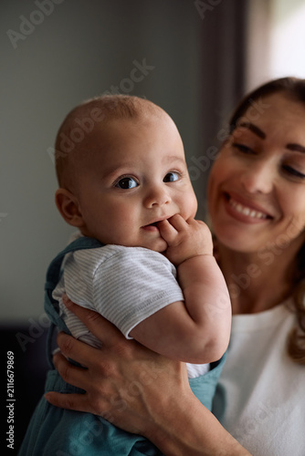 Bild auf Leinwand Cute baby boy enjoying in mother's arms at home.