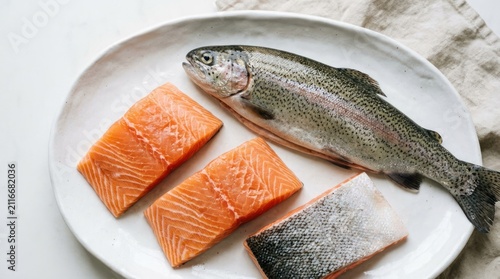 Fresh Whole Rainbow Trout and Salmon Fillets on a White Plate.