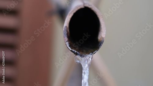 Extreme close up of water dripping from a pipe conceptualizing drought and water scarcity