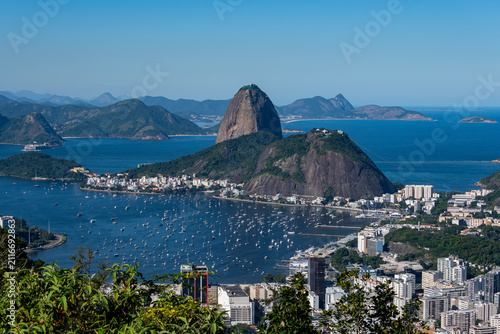 Fotografía The sweeping view of Sugarloaf Mountain highlights its imposing shape rising above Guanabara Bay, featuring green slopes, blue waters, and the sprawling city