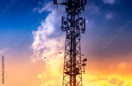 Fotografía Telecommunication tower silhouette against sunset sky