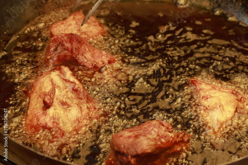 Pork meat cooking in hot lard for traditional Peruvian chicharrón