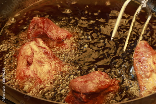 Pork meat cooking in hot lard for traditional Peruvian chicharrón