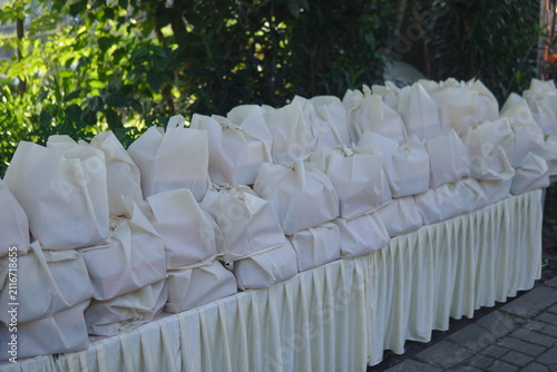 Fotografie Rows of white goodie bags and food boxes neatly arranged on a table for an outdoor event
